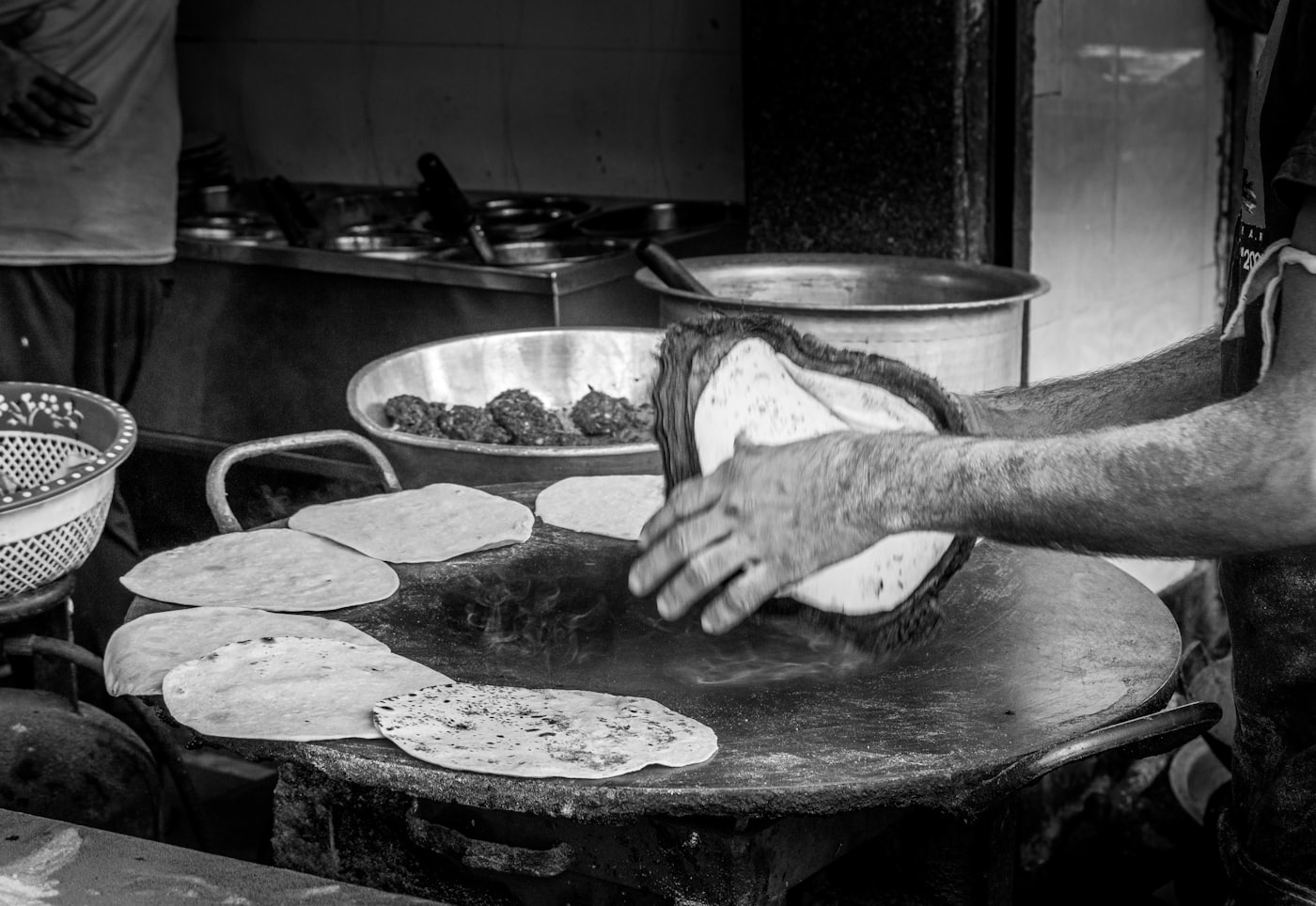 Le comal en plein service : tortillas de maïs disposées en couronne sur la plaque d'acier ronde, une main en retourne une dans la vapeur
