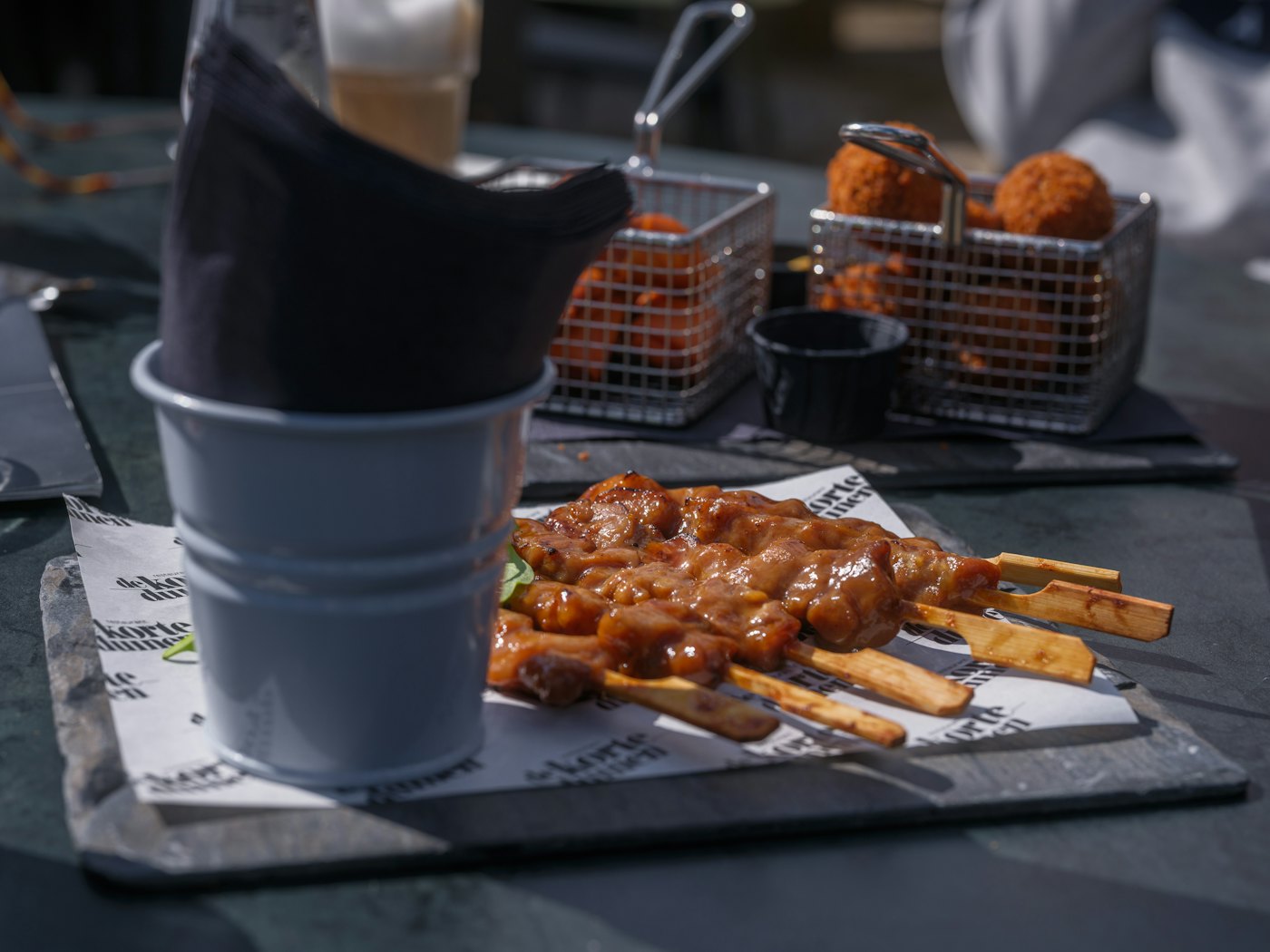 Brochettes yakitori dressées sur une ardoise noire, dans la pénombre de la salle